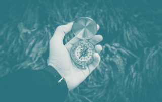 A hand holding a compass, symbolising a business navigating its path through market orientation by aligning with customer needs and competitive awareness.